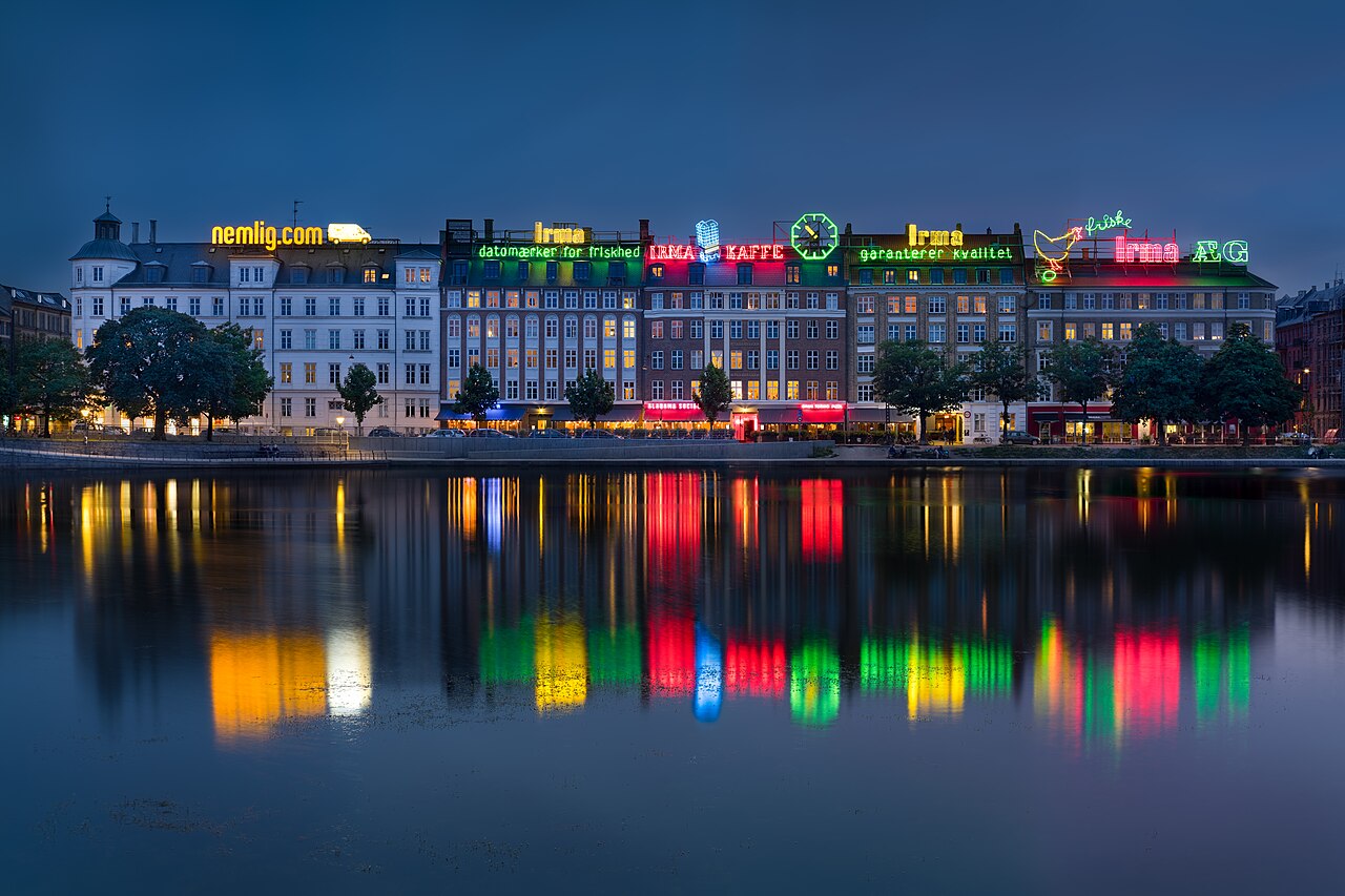 Panorama Kopenhagi nad jeziorami Sortedam Sø, z neonowym szyldem Irma Hen na budynku Irma Karréen. Zdjęcie wykonano 21 czerwca 2017 roku. Zdjęcie archiwalne; nie przedstawia opisywanego zdarzenia Plik bez zmian redakcyjnych; miniatura dopasowana do układu strony.